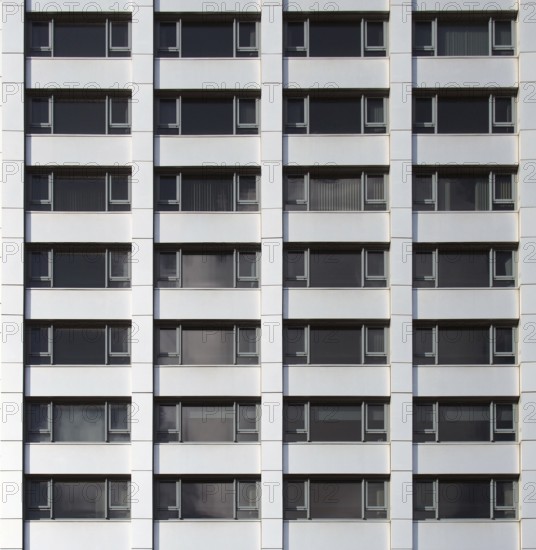 Front view of the facade of a modern commercial building with geometric repeating windows and grey cladding