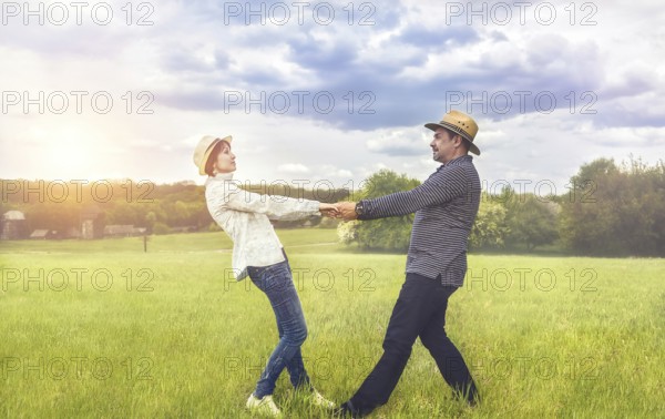 A portrait of a happy middle-aged couple holding hands in the green field