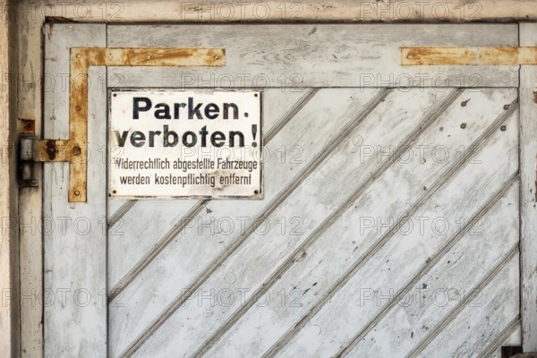 An image of a private no parking sign with german text Illegally parked vehicles will be towed at the owner's expense