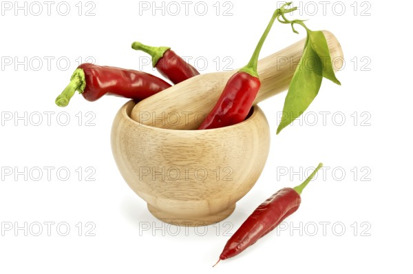 Three fresh chilli pepper with a green leaf in a wooden bowl and a pepper on the table isolated on white background