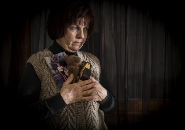 Senior woman hold pictures of childrens. Toys
