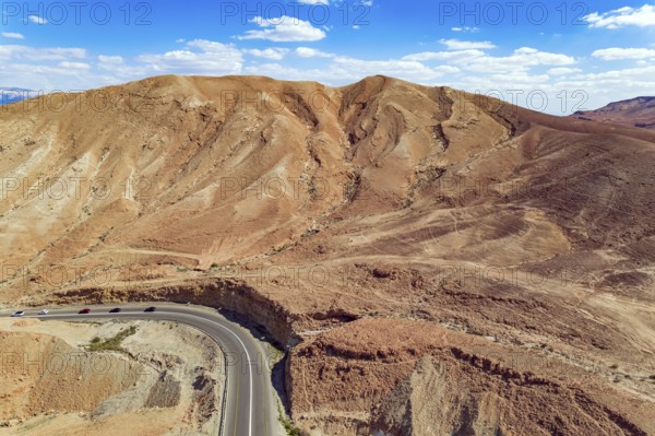 Judean desert on the shores of the Dead Sea. Dry waterless hills of yellow, beige and gray clay. Excellent roads - highways are laid among the hills. Shooting from a drone. Israel