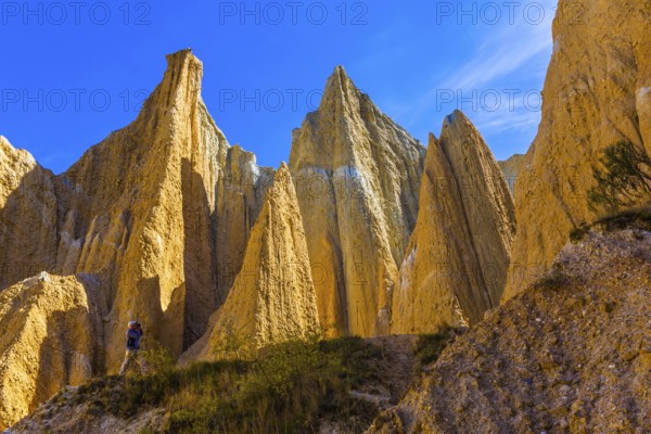 Elderly man takes pictures in the gorge. The Clay Cliffs are tall pinnacles separated by narrow ravines. Travel to New Zealand. The concept of active, eco and photo tourism