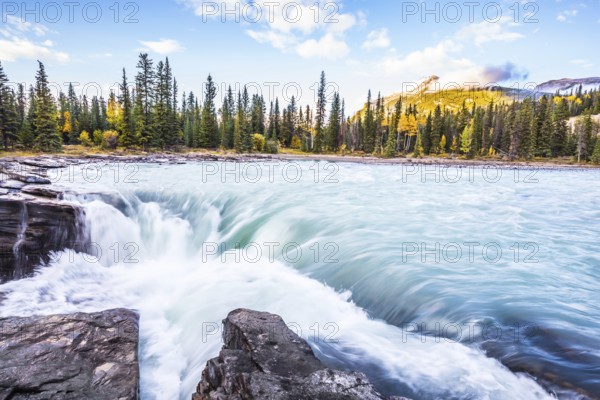 The full-water bubbling waterfall of Athabasca. Clear autumn evening in Canada. Cold blue water at sunset. The concept of extreme and ecological tourism