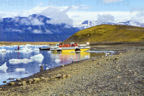 ICELAND, SCAFTAFETL PARK, ICE LAGOON JOKULSAURLOUN - July 10, 2014: Yellow boat for tourists. The icebergs and ice floes reflected in the water. The concept of northern and photo tourism