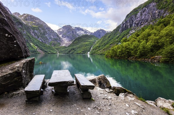 Cozy tourist wooden table and benches on the shore. Picturesque mountain lake Bondhuswatnet. Gorgeous mountainous Norway. Evening soft twilight
