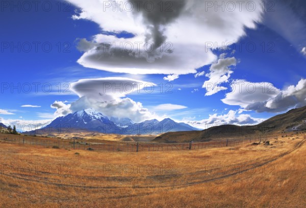 The Chile National Park Torres del Paine. Incredible shaped clouds formed by glaciers glisten in the sun. On the horizon are seen mountains with snow-capped peaks. Picture taken with a fisheye lens