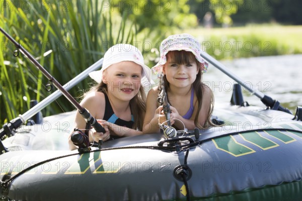 Little girls fishing on lake at summer