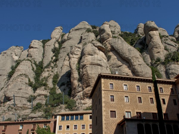 Building at the foot of rocky mountains under a clear sky in Montserrat, montserrat, spain