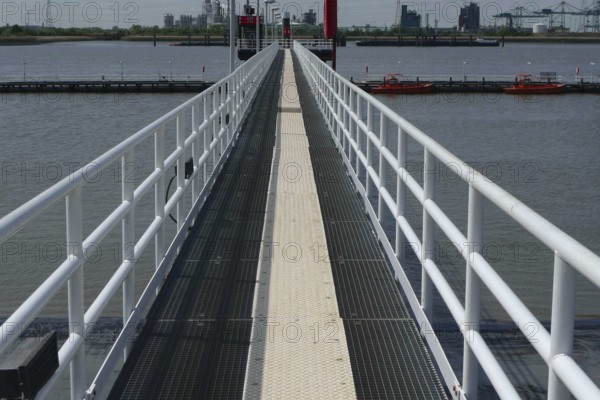 Metal walkway over the water, flanked by boats and an industrial backdrop, lillo, antwerp, belgium