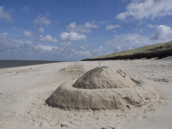 Beach landscape with a large sandcastle under a blue sky, spiekeroog, east frisia, north sea, germany