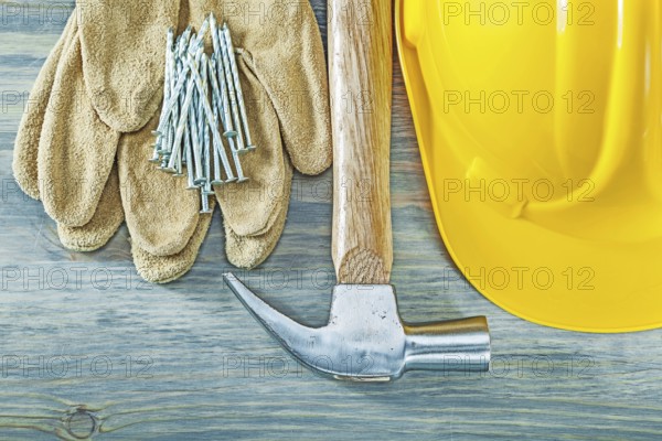 Hard hat protective gloves claw hammer nails on wooden board construction concept