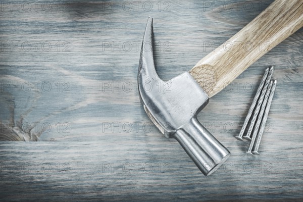 Claw hammer nails on vintage wooden board construction concept