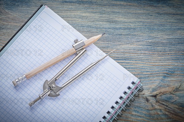 Vintage pair of compasses pencil open blank copybook on wooden board construction concept