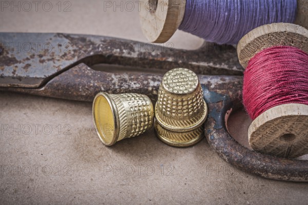 Reels of sewing threads thimbles scissors on vintage background