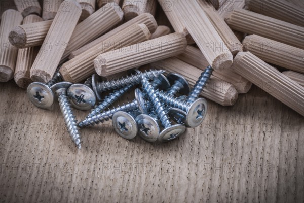 Woodworking dowels and construction nails on wood board top view
