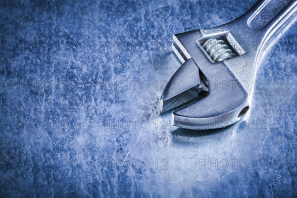 Copy space of stainless adjustable wrench on scratched metallic background construction concept