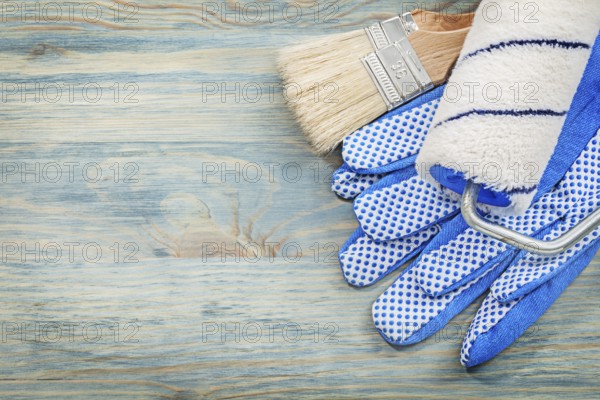 Paint roller brushes protective gloves on wood board construction concept