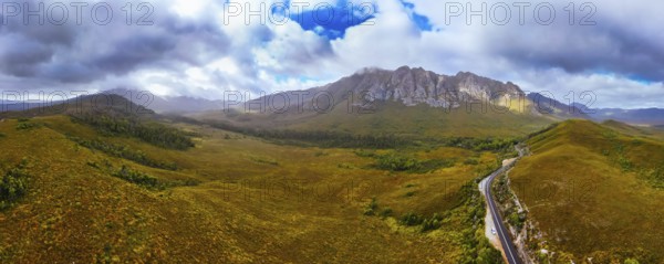 An aerial view of Gordon River Rd at the Sentinel range of mountains near Bitumen Bones Sculpture on a hot summer's afternoon in Southwest National Park, Tasmania, Australia