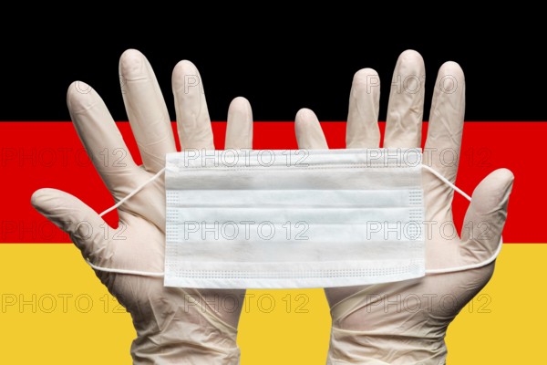 Doctor holding medical face mask in two hands in white gloves on background flag of Germany. Concept coronavirus quarantine, hygiene, grippe, pandemic outbreak. Medical respiratory bandage for face