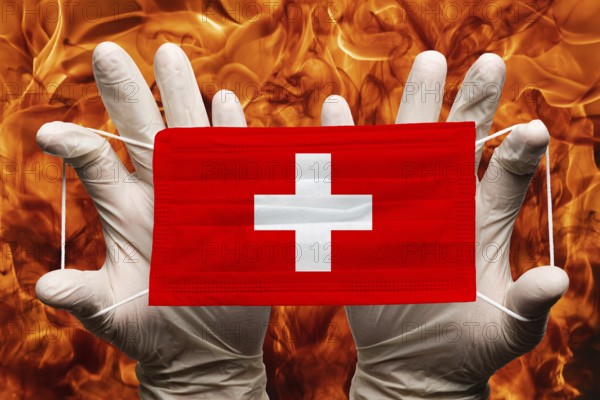 Doctor holding in white gloves protection medical face mask, respiratory bandage with Switzerland national country flag superimposed on mask. Concept on background of dangerous red flames natural fire