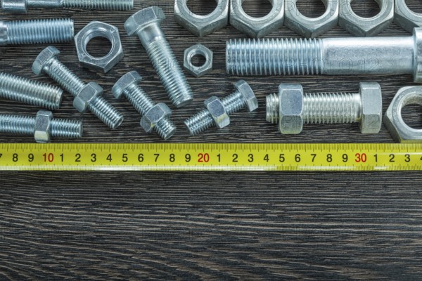 Bolts nuts tape measure on wooden board
