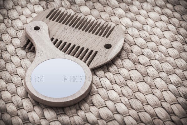 Wooden hand glass and comb on wicker mat healthcare concept