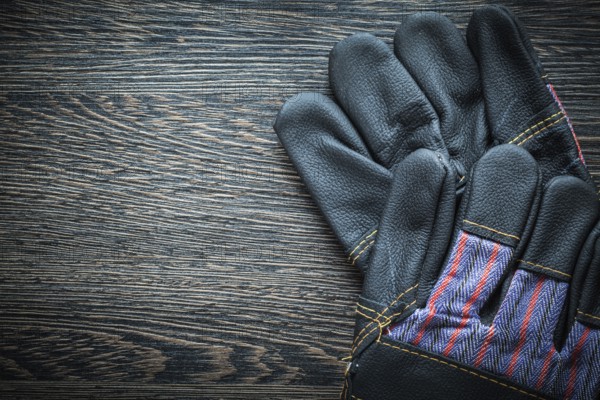 Pair of leather protective gloves on wooden board