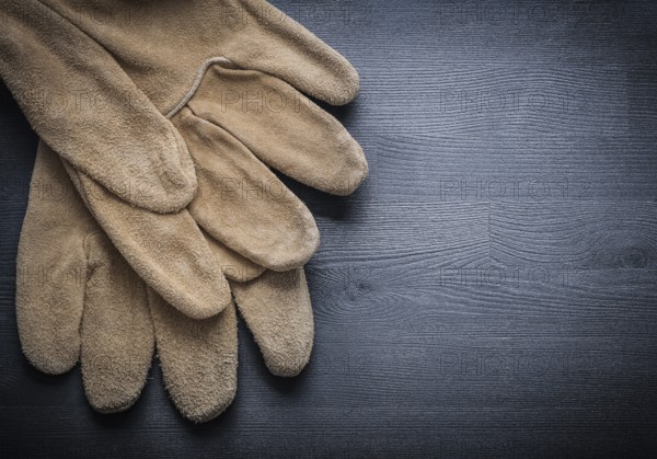 Two working leather gloves on dark wood board