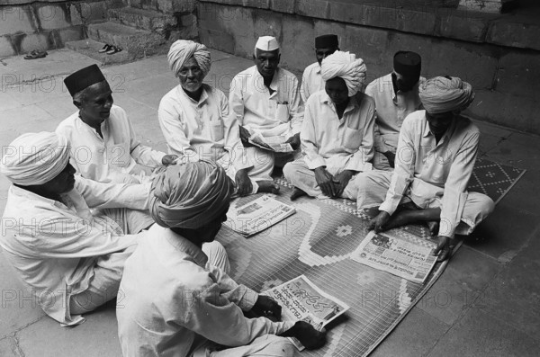 Rural people seating in group and reading news papers, Munagoli village, Bijapur district, Karnataka, India