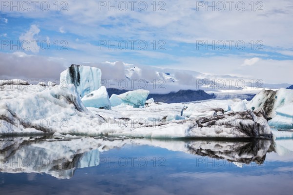 Icebergs and ice floes are reflected in the mirrored water of the ocean Bay. Ice lagoon in July. Summer vacation in Iceland