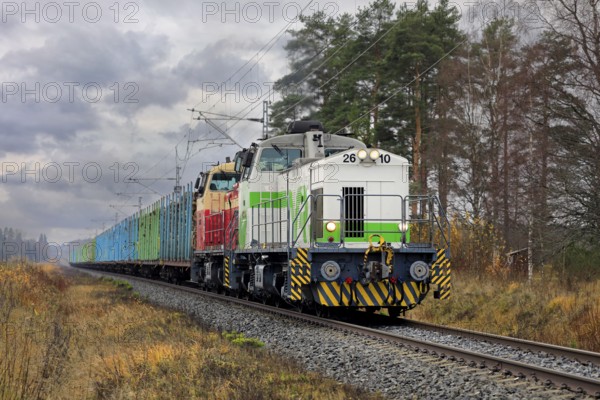 VR freight train with two diesel locomotives and carriages full of wood logs on the move on a day of autumn. Humppila, Finland. October 30, 2020