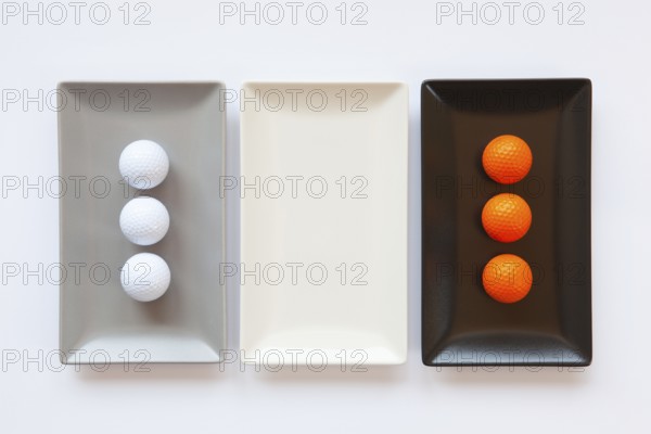 Different ceramic dishes with golf balls on over white background, rectangle dish