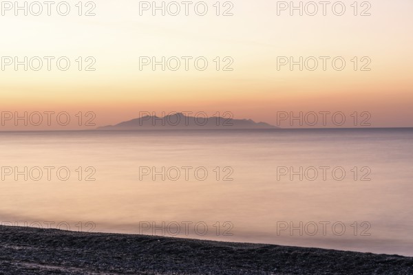 Dawn at sunrise, view from the lava beach near Kamari to the island of Anafi, long exposure, island of Santorini (Thira), Cyclades, Greek Islands, Greece