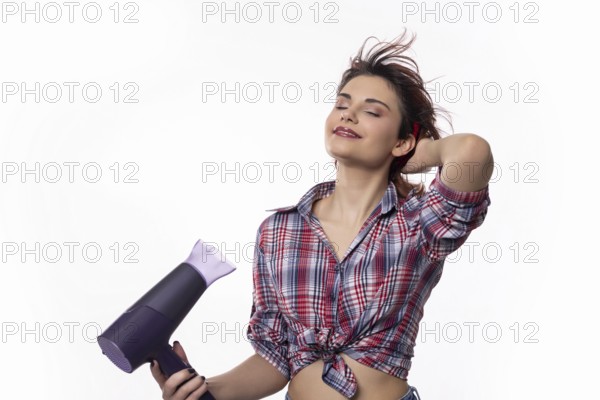 A confidently poised woman happily using a hair dryer, joyfully showcasing beautiful hair styling trends