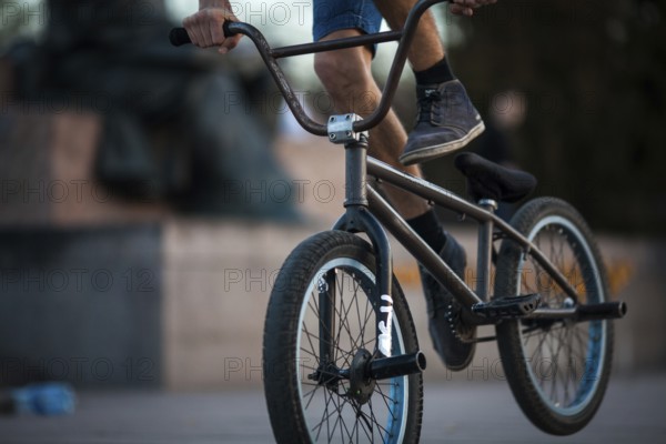 Young teenager bicyclist boy riding on beautiful orange bmx bicycle male hobby extreme sport male hobby lower part closeup on natural background outdoors