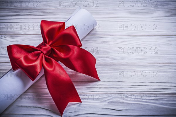 Roll of paper with red bow on wooden board holidays concept