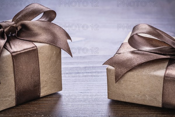 Two vintage pepr giftboxes with brown bows on old wooden board very close up view holiday concept