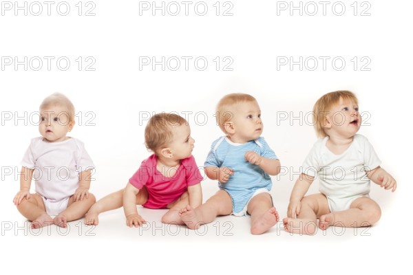 Group of witty babies sitting in different clothes, isolated on white background