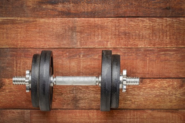 Heavy iron dumbbell on a rustic wood background - fitness concept