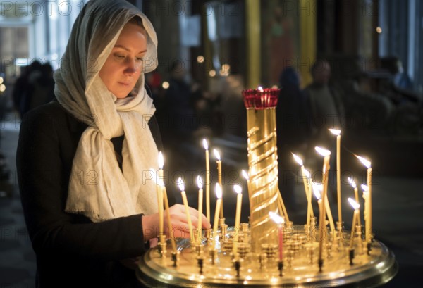 Woman lights the candle in russian orthodox church