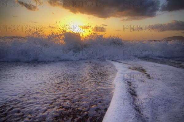 Gentle warm sea on backdrop of enchanting sunset. Foamy surf. Mediterranean sea