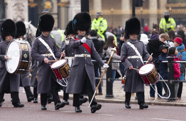 A parade of British guards in ceremonial uniform with black bearskin hats and flags marching in the City of Westminster, Greater London, United Kingdom