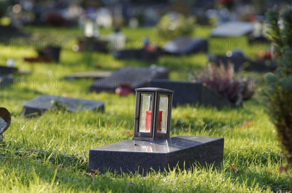 Grave lantern on a gravestone of a cemetery with graves of the poor in front of a blurred background