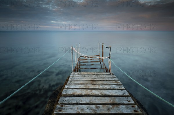 Long wooden pier in the sea at sunset. Protaras Cyprus