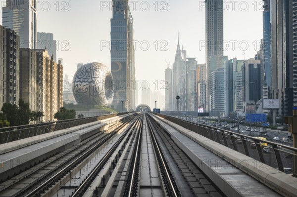Dubai, UAE - 11.3.2022: Dubai Metro rail with skyscrapers and Museum of the Future in Dubai in the frame. Dubai Cityscape skyline with modern urban transit system