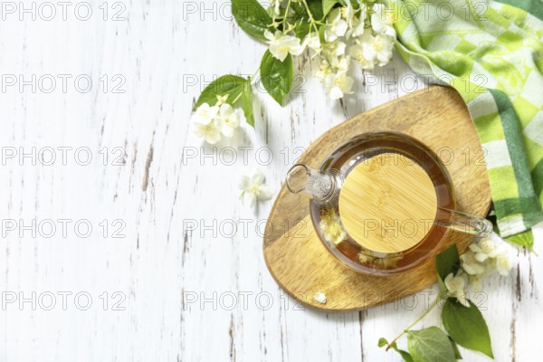 Therapeutic herbal tea. Hot Jasmine tea with jasmine flowers in a glass teapot on a rustic wooden table. Top view flat lay background. Copy space