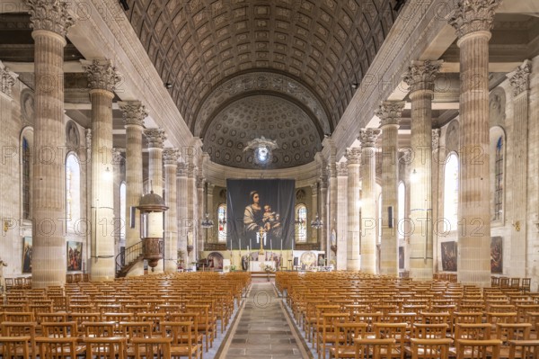Neoclassical church interior of the Eglise Saint-Louis with monumental columned peristyle of rudentated and fluted Corinthian columns, continuous entablature, imposing wood-panelled barrel vault ceiling with coffered structure and painted rosettes in trompe-l'oeil, flooded with light through Renaissance glazing and Madonna and Child as central altar motif, La Roche sur Yon, Vendee, Pays de la Loire, France