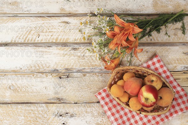 Summer berries and fruits on a wooden background with lilies and daisies, harvesting in the village, healthy natural food concept, breakfast with ingredients, store advertisement, business card for cafe, selective focus