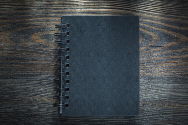 Black spiral notebook on vintage wooden board
